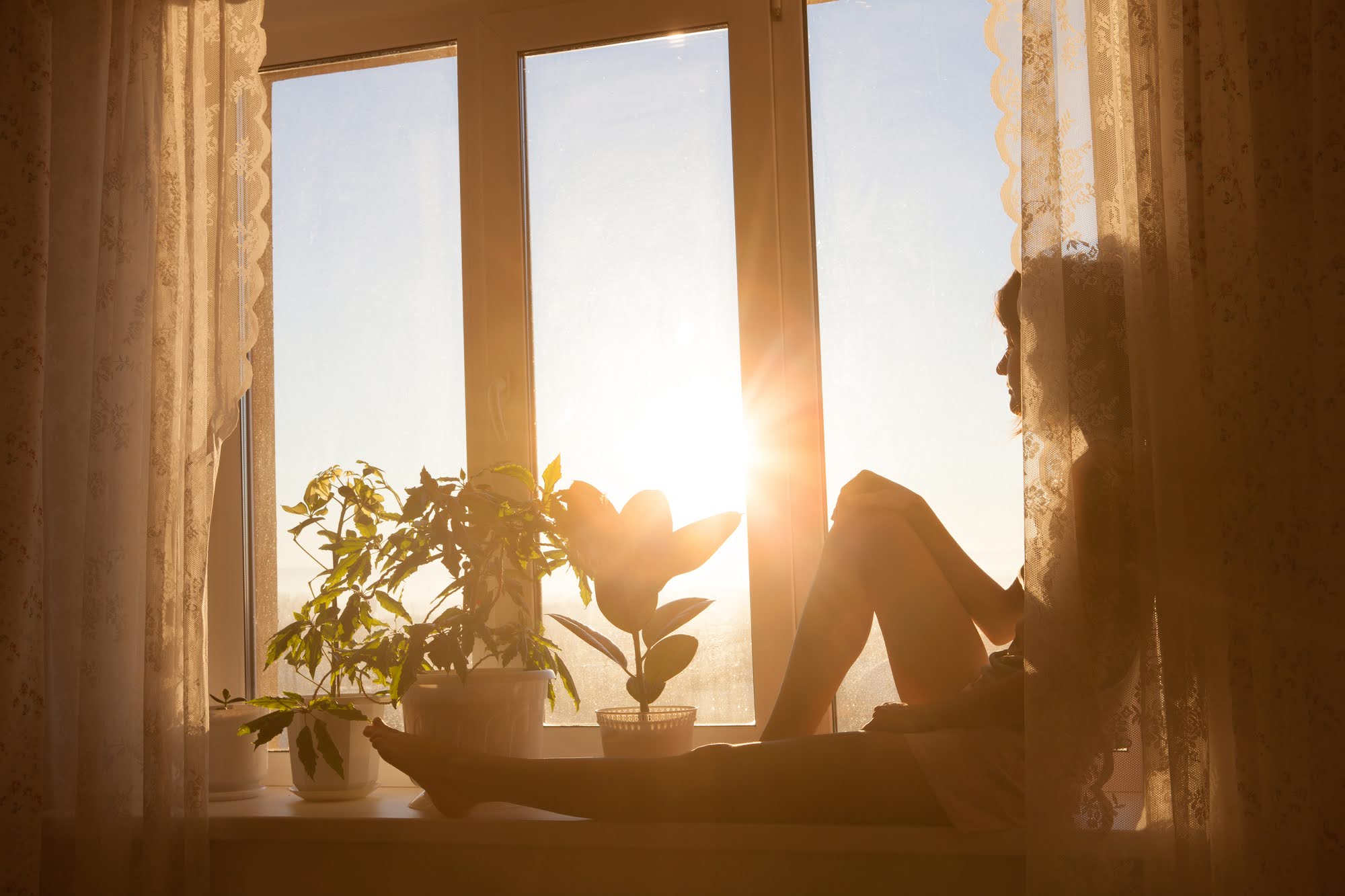 Woman sitting at window watching sunrise